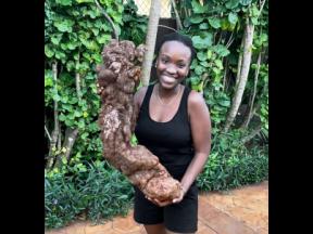 Justine Harrison poses proudly with the yam she harvested from her backyard, which weighed approximately 26 pounds.