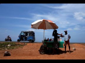 A man buys a cool drink from a roadside vendor on a sunny day in Mahawewa, a village north of Colombo, Sri Lanka, February 29, 2024. A new study says climate change will reduce future global income by about 19% in the next 25 years compared to a fictional 