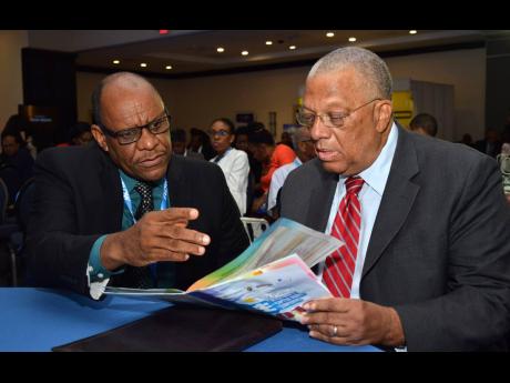 Ian McNaughton, chairman of the Jamaica Stock Exchange (JSE), makes a point to Opposition Leader Dr Peter Phillips  at the JSE Conference at The Jamaica Pegasus yesterday.