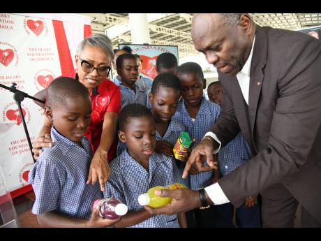 Fitzroy Henry, professor of public health nutrition at the University of Technology (UTech), and consultant cardiologist Dr Andrene Chung, chairman of the Heart Foundation of Jamaica (HFJ), chat with students from Seaward Drive Primary School about sugary drinks as the Heart Foundation of Jamaica launches Phase 4 of the ‘Are We Drinking Ourselves Sick?’  campaign at the Half-Way Tree Transport Centre yesterday.