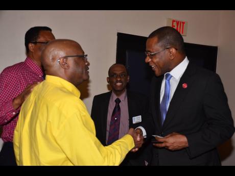 Past president of the Rotary Club of Kingston Francois St Juste (left) welcomes Courtney Campbell (right), president and CEO, Victoria Mutual Group, to the recent Rotary Club of Kingston’s luncheon meeting. Looking on are Rotarians Neville Henry (partially hidden background left) and  Andre Gooden.