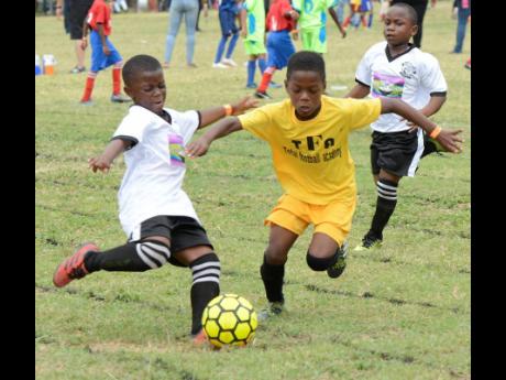 Conner James (centre) from Total Football Academy, is challenged by Zack Wright from Norbrook Strikers during the Victory Cup youth football competition, which was held at Shortwood Teacher’s College on Saturday. Looking on is Norbrook’s Didier Dunbar (right).