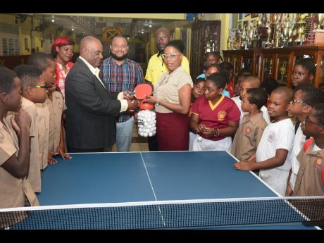 Godfrey Lothian, president, Table Tennis Jamaica, makes a presentation of table tennis racquets, balls and a table to Ms Janet Howard, principal, Wolmer’s Preparatory School, at the institution yesterday. Along with curious students, others looking on (from left) are PTA President Lisa Reynolds, Board Chairman Ryan Foster and coach Raymond Leveridge.
