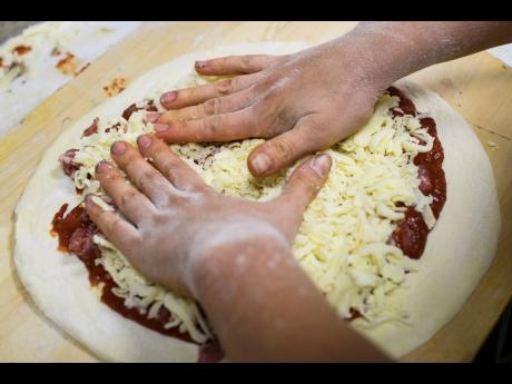 In this September 26, 2018 file photo, a worker adds cheese to a raw pizza at a shop in Pittsburgh, USA.