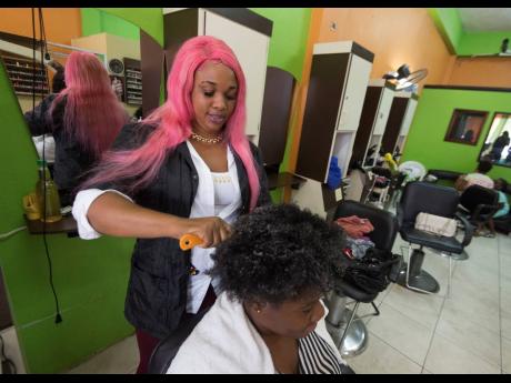 Serita Nelson, a hairdresser at Glitz and Glam Beauty Salon in Portmore Pines, St Catherine, tends to her client, Donae Martin, yesterday. Nelson and other members of the micro, small, and medium enterprise sector stand to benefit from tax-relief measures such as the abolition of the minimum business tax of $60,000. 