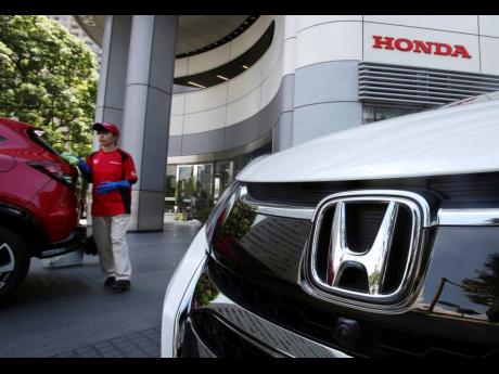 In this July 31, 2018, file photo, an employee of Honda Motor Company cleans a Honda car displayed at its headquarters in Tokyo.