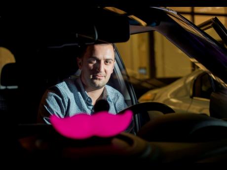 In this January 26, 2015, file photo, Lyft co-founder John Zimmer displays his company’s ‘glowstache’ following a launch event in San Francisco.