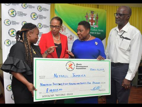 Minister of Culture, Gender, Entertainment and Sport  Olivia Grange (second right) hands over a cheque for £19,835 (approximately J$3.5 million) to the first vice-president of Netball Jamaica, Patricia Robinson (left), to assist with funding the Sunshine Girls for the 2019 World Cup in Liverpool.  Looking on are Molly Rhone (second left), president, International Netball Federation, and Denzil Wilks, general manager, Sports Development Foundation.  