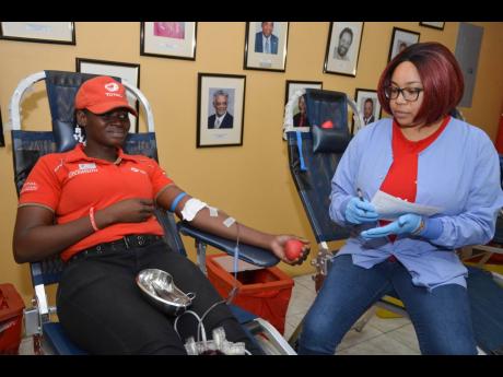 A nurse at the blood bank, Catherine Treasure, overseas the collection of blood from Total’s Tracy Gentles during the Jamaica Gasolene Retailers Association’s blood drive on Wednesday at the association’s office at Kings Plaza, Kingston.