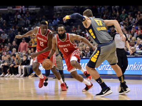 Houston Rockets guard James Harden (13) drives between teammate Clint Capela (15) and Memphis Grizzlies centre Jonas Valanciunas (17) during the second half of an NBA basketball game on Wednesday night in Memphis, Tennessee. The Grizzlies won 126-125 in overtime.