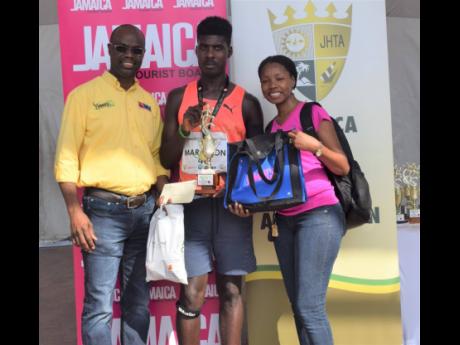 Male winner of the Kingston City Marathon, Oshane Archibald (centre) pose with Jamaica Tourist Board representatove Maureen Smith (right) and NMIA official Alfred McDonald. 