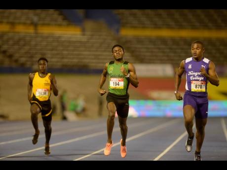 Calabar’s Christopher Taylor (centre) crosses the line in the Class One boys 200m heats ahead of  Kingston College’s Oshane Peart at the ISSA/GraceKennedy Boys and Girls’ Athletics Championships at the National Stadium last night. Taylor clocked 21.69 seconds for the win.