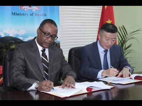 Permanent Secretary in the Ministry of Health Dunstan Bryan (left) and Chinese Ambassador Tian Qi ink the memorandum of understanding for the Bright Journey Eye Care Mission to Jamaica at the Ministry of Health’s head office on March 14.