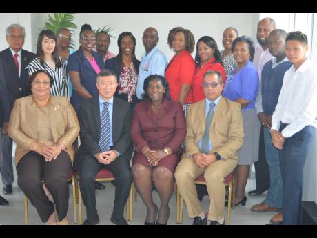 Chinese ambassador to Jamaica, Tian Qi (second left, seated), with principal of the Montego Bay Community College, Dr Maureen Nelson (third left, seated), and members of her academic staff pose in a corner for The Gleaner’s photographer away from the displayed official photograph of Ruel Reid. 