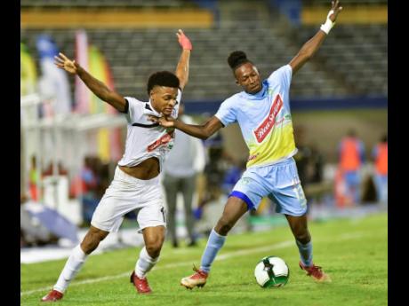 Alex Marshall (left) of Cavalier FC and Waterhouse's Ricardo Thomas in a tussle for possession of the ball in the Red Stripe Premier League second leg semi final played at the National Stadium in Kingston earlier this evening.