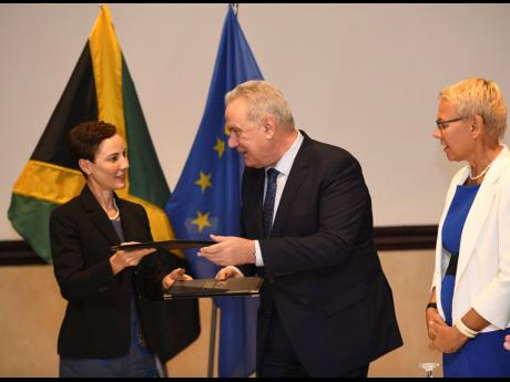From left: Foreign Affairs Minister Kamina Johnson Smith exchanges documents with Nevin Mimica, European commissioner for international cooperation and development, and Malgorzata Wasilewska, head of the European Union Delegation to Jamaica, after a signing ceremony for improved forest management and support for public financial management reform between the Government of Jamaica and the European Union at The Jamaica Pegasus hotel yesterday.