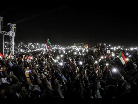 Sudanese protesters use their smartphones’ lights during a protest outside the army headquarters in the capital Khartoum on Sunday, April 21, 2019. 