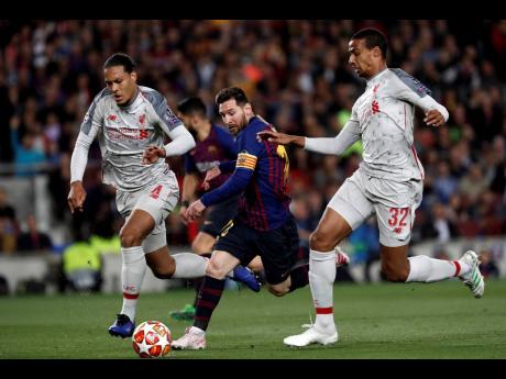 Barcelona’s Lionel Messi runs with the ball between Liverpool’s Virgil Van Dijk (left) and Joel Matip (right) during the Champions League semi-final first-leg match between FC Barcelona and Liverpool at the Camp Nou stadium in Barcelona Spain, yesterday.  Barcelona won 3-0