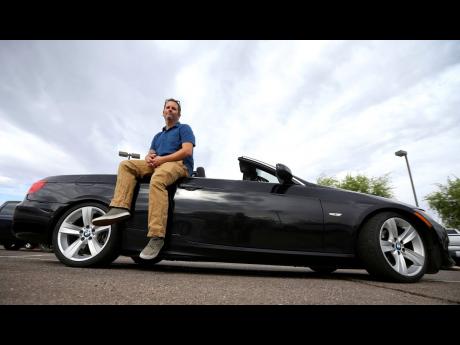 Chris Williamson poses for a photo sitting on his car in Phoenix on In this April 23. Williamson bought a BMW 3 Series convertible and covers the payments by renting it to strangers on a peer-to-peer car sharing app called Turo.