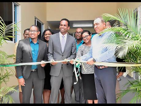 Floyd Green (left), member of parliament for St Elizabeth South West; Carey Wallace (centre), executive director of the Tourism Enhancement Fund; and Health Minister Dr Christopher Tufton participate in the ribbon cutting for the expanded Black River Health Centre in St Elizabeth. 