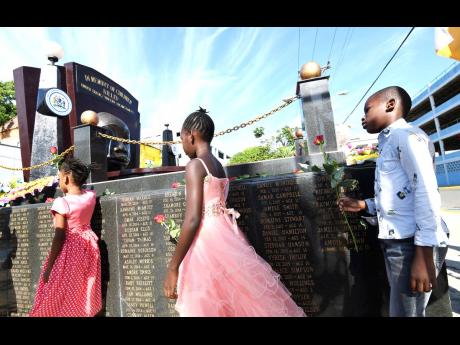 Children proceed to lay roses during the wreath-laying ceremony at the Crying Child monument at Secret Gardens in downtown Kingston yesterday in memory of the hundreds of children who have died under tragic circumstances during Child Month activities.