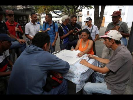 People play dominoes in Candelaria Plaza in Caracas, Venezuela, yesterday. The South American country is still going through a period of political uncertainty with Opposition Leader Juan Guaido’s challenge to the rule of President Nicolás Maduro.