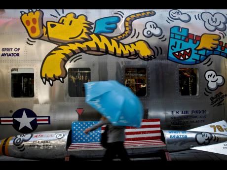A woman walks by a bench painted with an American flag outside a fashion boutique selling US branded clothing at the capital city’s popular shopping mall in Beijing, Monday, May 13.