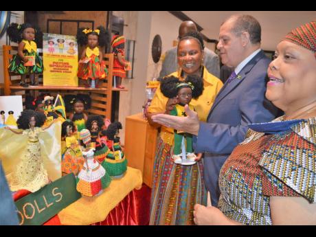 In this May 2018 photo, president of Island Dolls Plus Collection, Beverley Robotham-Reynolds (left), shows Minister of Industry, Commerce, Agriculture and Fisheries Audley Shaw the company’s line of dolls, during a tour of exhibits, at the 11th Annual Jamaica Business Development Corporation’s (JBDC) Small Business Expo and Conference, held at The Jamaica Pegasus hotel, New Kingston.  At right is Chief Executive Officer of JBDC Valerie Veira.
