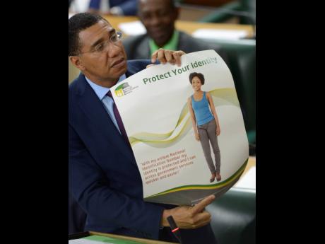 Prime Minister Andrew Holness shows a poster which he said was produced by the former Portia Simpson Miller-led administration to promote the National identification System during yesterday’s sitting of Parliament.
