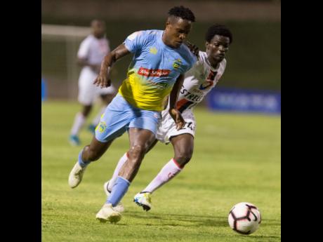 Stephen Williams (left) of Waterhouse dribbles to goal while under pressure from Jim Cerant of Real Hope during their 2019 FLOW Concacaf Caribbean Club Championship match at Stadium East yesterday. Waterhouse won 2-0.