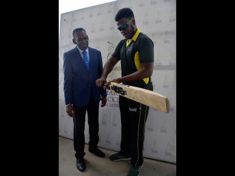 Javelle Glenn (right), captain of Melbourne CC, demonstrates the proper way to hold a cricket bat to Billy Heaven, president of the Jamaica Cricket Association, during the launch of the Jamaica Cricket Association Jam T20 Bashment Cricket Competition at Sabina Park, yesterday.