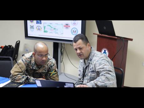 A member of the DC National Guard examines Jamaica’s National Disaster Action Plan with a Jamaica Defence Force soldier, as part of a military-to-military planning exercise recently. 
