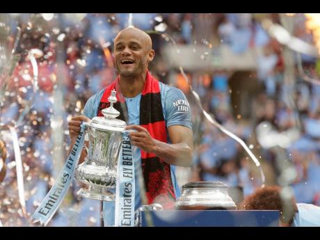 Manchester City’s team Vincent Kompany lifts the trophy after winning the English FA Cup final against Watford at Wembley Stadium in London, England, on Saturday. City won 6-0. 