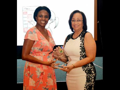 Professor Maureen Samms-Vaughan (right), former chairman of the Early Childhood Commission, accepting her award from Trisha Williams-Singh, the current chairman.