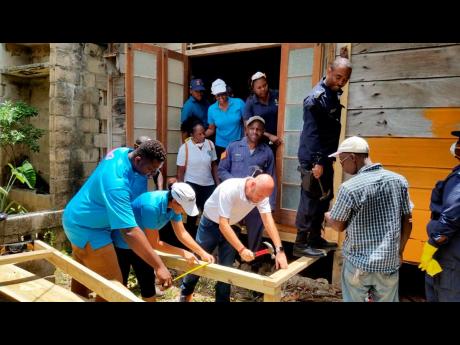 A work crew from the Royalton White Sands, Trelawny police and Rotaract Club of Falmouth repairs the ageing home of 100-year-old Boris Anderson in Martha Brae, Trelawny. 
