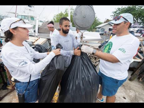 Members of Team Mama Mia, Bianca Bovell (left) and Jonathan Kerr (centre), are assisted by Nicholas McKoy in weighing in trash collected from the sea in the Trash Tournament held at the Royal Jamaica Yacht Club in Kingston on Thursday. Team Mama Mia won with a haul of 1,988 pounds of trash. 