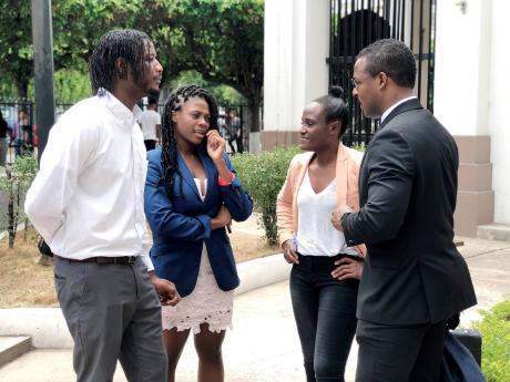 From left: Siblings of fashion designer Dexter Pottinger – Danta Aarons, Ta-Shan Adams, Lakeisha Aarons – speaking with attorney-at-law Duane Thomas outside of the Supreme Court in downtown Kingston yesterday. 