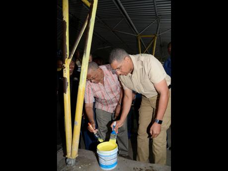Prime Minister Andrew Holness (right) and Opposition Leader Dr Peter Phillips help to paint a section of Papine High School at one of the four National Labour Day Projects on Thursday. 