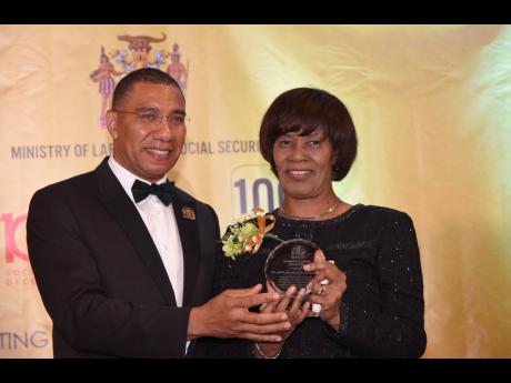 File
Prime Minister Andrew Holness (left), presents a plaque to Former Prime Minister, Portia Simpson Miller, in recognition of her contribution to the labour movement. Occasion was the Ministry of Labour and Social Security’s awards banquet in celebration of the centenary of the International Labour Organization and the Trade Union Act of Jamaica at The Jamaica Pegasus hotel, New Kingston, on Wednesday May 22.