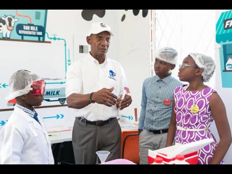 Livingston Binns, sales and marketing manager at Island Dairies, explains the process of testing milk for bacteria to students of Monsignor Colin Bryan Preparatory School.