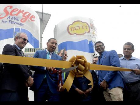 Prime Minister Andrew Holness cuts the ribbon signifying the official launch of the consolidated Serge Island Dairies plant at Bogwalk, St Catherine on Tuesday, May 28. The prime minister is flanked by (from left in the foreground), Chairman of Seprod Paul Scott,  Seprod CEO Richard Pandohie, and Opposition spokesman Noel Arscott. Minister of Industry, Commerce, Agriculture and Fisheries Audley Shaw is partially seen in the background. 
