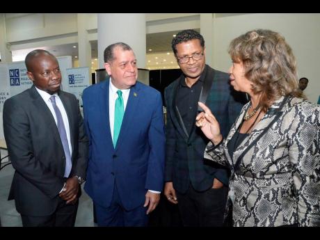 Diane Edwards (right), president of JAMPRO, has the rapt attention of (from left) Ian Mitchell, director of the Trinidad and Tobago Manufacturers’ Association; Audley Shaw, minister of industry, commerce, agriculture and fisheries; and Richard Pandohie, CEO of Seprod, at yesterday’s official opening of the Jamaica International Exhibition at the Montego Bay Convention Centre in St James. 