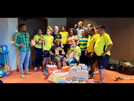Jamaica’s senior women’s football team and head coach Hue Menzies (right) receive home comforts from members of the Jamaica Association in Switzerland in Lyon, France, yesterday. 