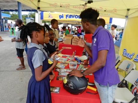 Primary-school students seeking information at the road-safety booth in Golden Grove, St Ann, on Wednesday. 