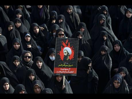 In this January 4, 2016 file photo, an Iranian woman holds up a poster showing Sheikh Nimr al-Nimr, a prominent opposition Saudi Shiite cleric who was executed by Saudi Arabia.  
