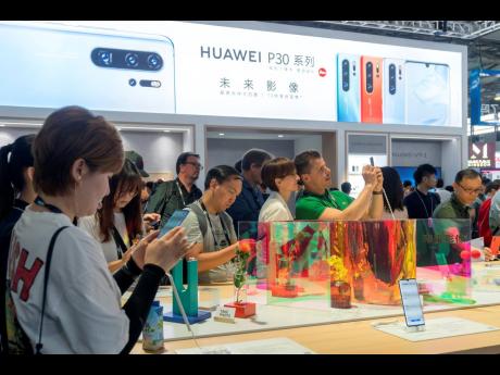 Visitors look at a display of smartphones from Chinese technology firm Huawei at the Consumer Electronics Show in Shanghai on Tuesday, June 11. 