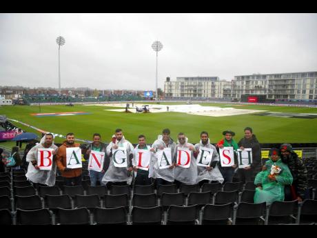 Bangladesh cricket fans display their allegiance as they stand in the rain during the ICC Cricket World Cup group-stage match at the County Ground in Bristol, England, yesterday. Bangladesh were scheduled to play Sri Lanka yesterday,
 but the match was rained out. 