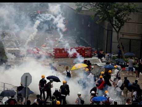 Riot police fire tear gas to protesters outside the Legislative Council in Hong Kong, Wednesday, June 12, 2019. Hong Kong police have used tear gas and high-pressure hoses against thousands of protesters opposing a highly controversial extradition bill outside government headquarters. (AP Photo/Vincent Yu)
