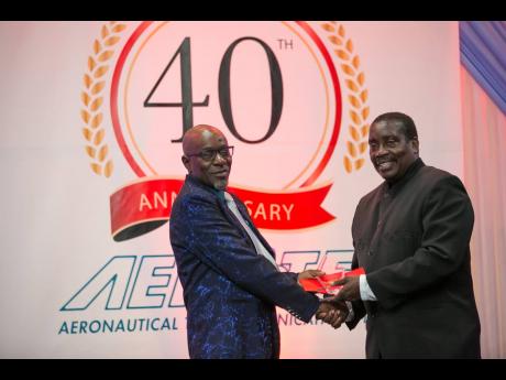 AEROTEL’s longest-serving staff member, Rowell Hall (left), accepts a plaque from Minister of Transport Robert Montague in recognition of his 30 years of service to the company. 