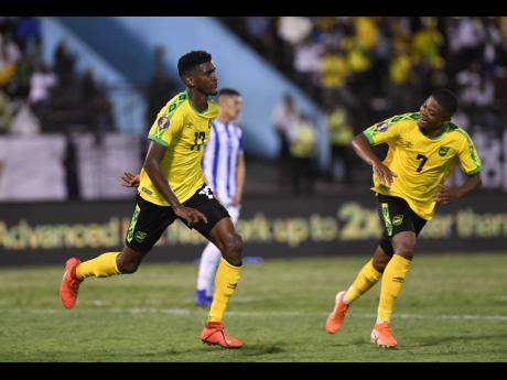 Jamaica's Damion Lowe (left) runs off in celebration with teammate Leon Bailey after netting the team's third goal in their 3-2 win over Honduras in their Group C clash in the Concacaf Gold Cup at the National Stadium tonight.